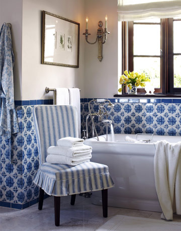 Bathe in Blue:  The master bathroom wainscoting of Portuguese glazed tiles was installed by the former owner's decorator. "Aren't they gorgeous?" says Nye. He slipcovered a Pottery Barn side chair in a complementary blue-and-white linen stripe from Rogers & Goffigon. 