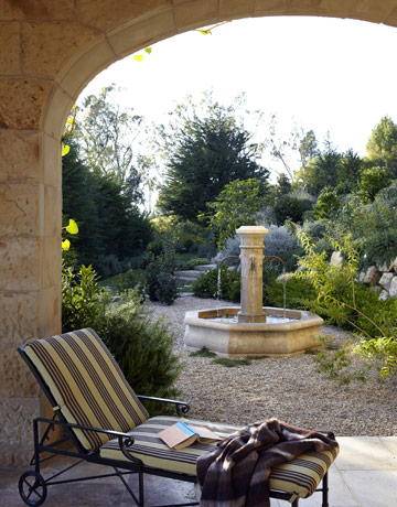 Recline in Rustic Style:  A Brown Jordan chaise stretches out near a limestone fountain. Rustic steps climb the lushly planted hillside that overlooks the Pacific. 